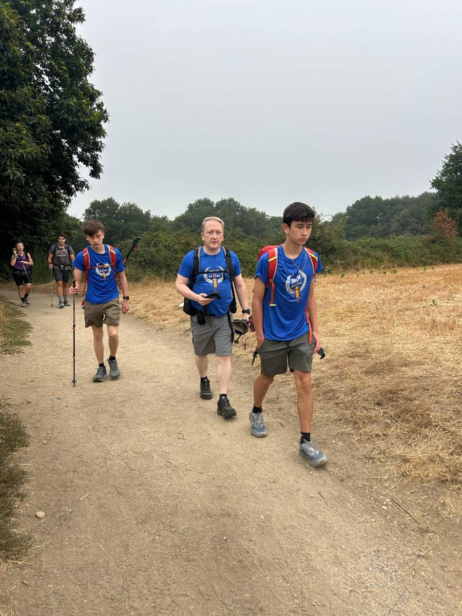 Peter and two teenagers in Break or Become shirts walking toward the camera on a dirt path.