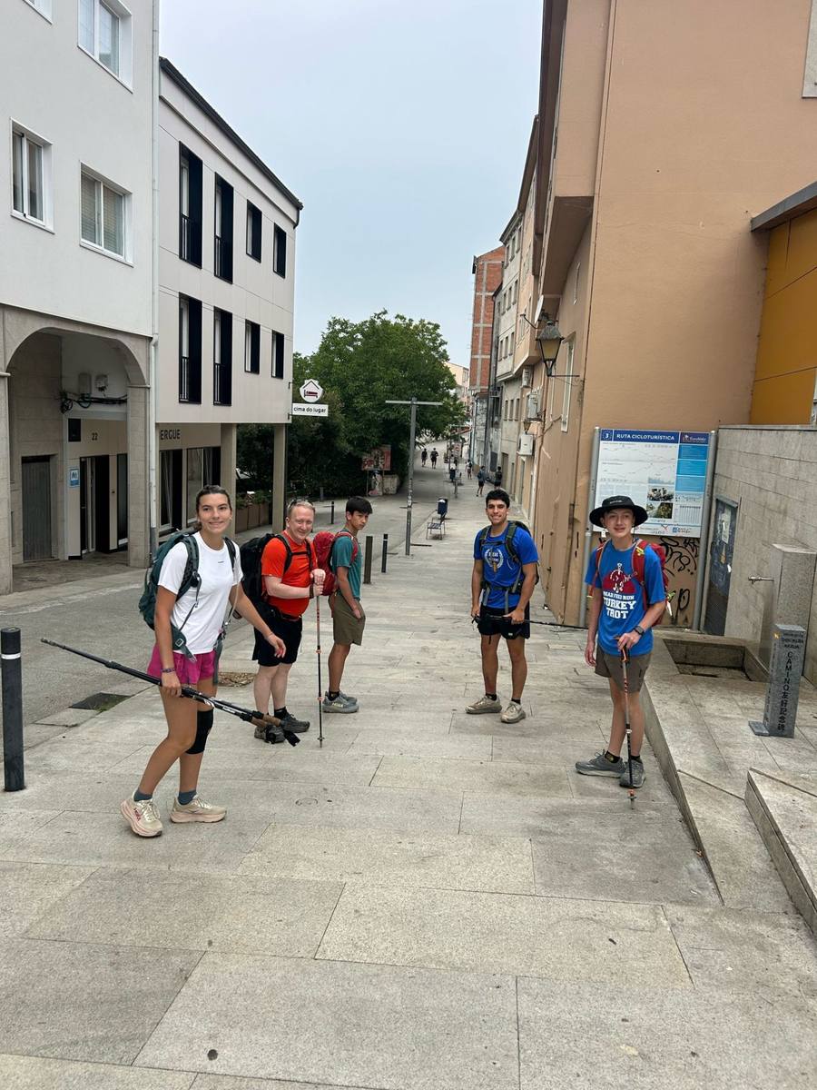 The group pausing on a paved street in a Galician town, poles in hand.